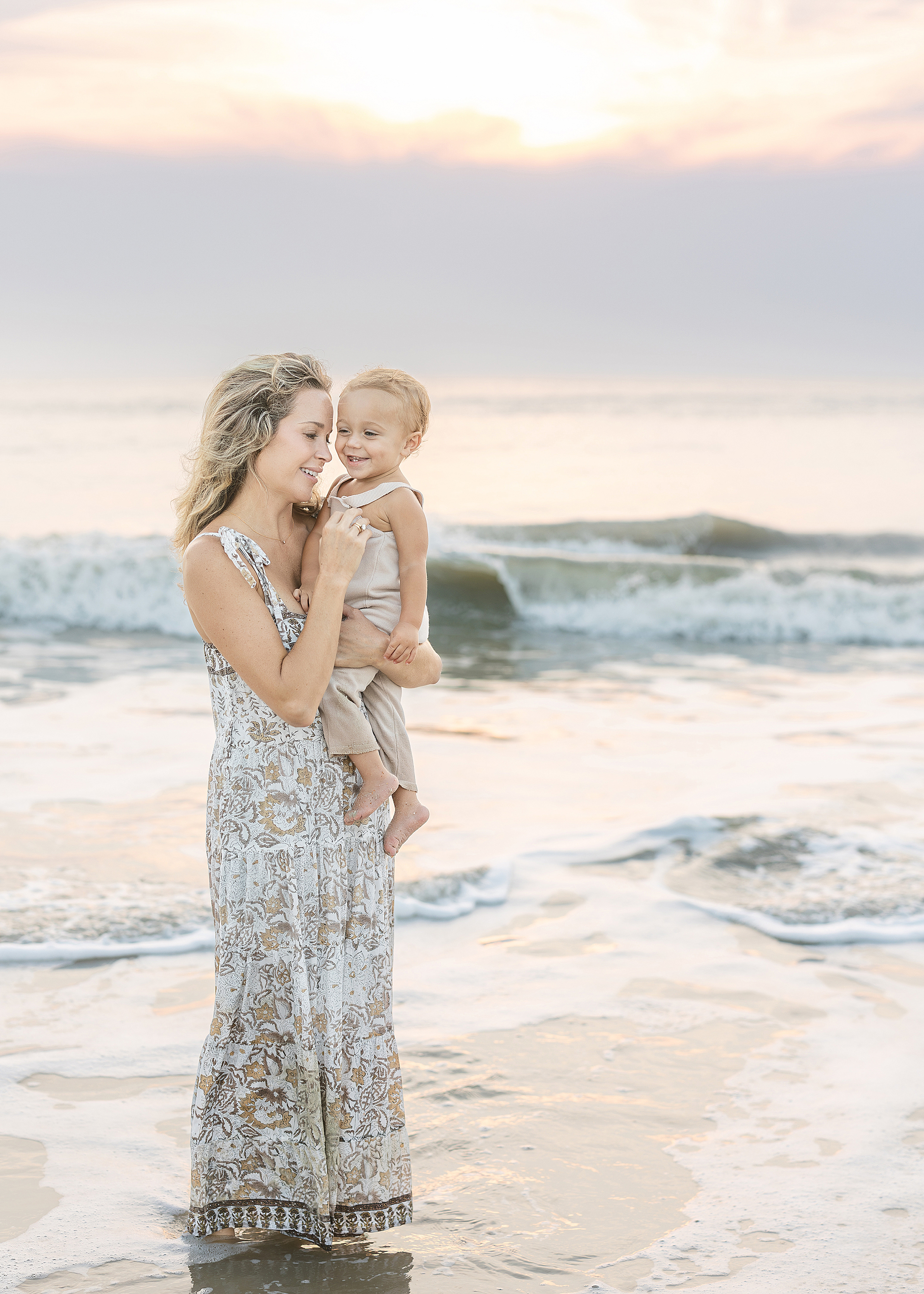 A sunrise motherhood portrait of a woman and her one year old boy on St. Augustine Beach at surnise.