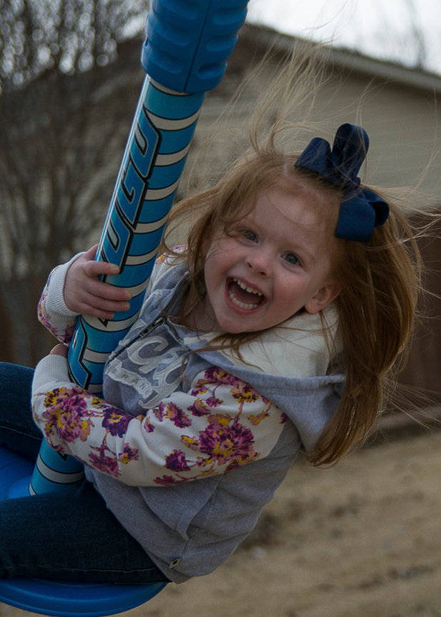 Young red headed girl having a big laugh on a swing.