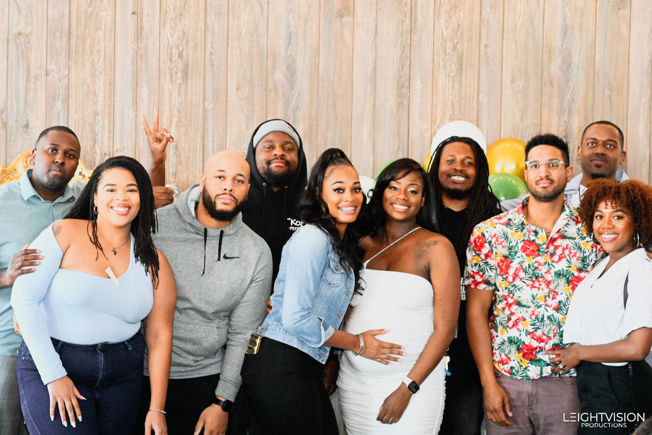 A group of individuals smiling and posing together for a photograph at a lively party setting.