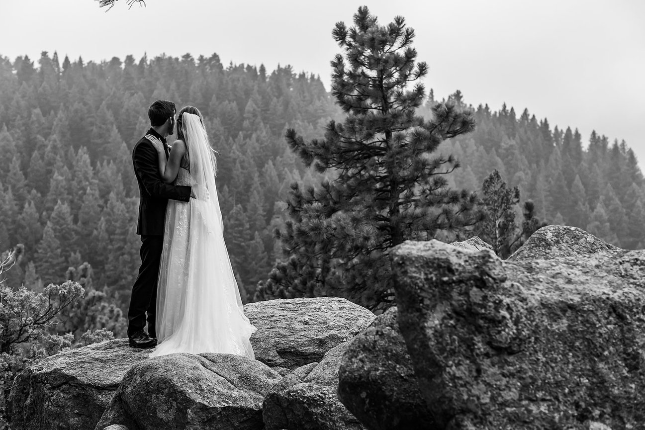 Bride and groom kissing on rocky cliff