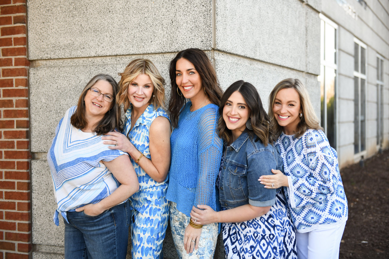 Group of five smiling women dressed in blue standing outside a professional building during a branding session in Winston-Salem, NC