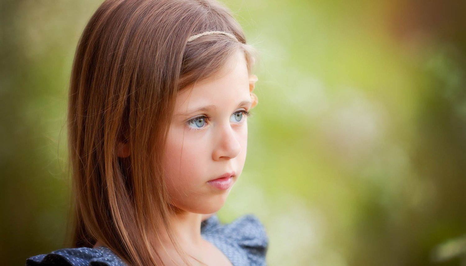 Color close-up portrait of a young girl serenely looking to the side, captured in soft natural light with a fine art approach.