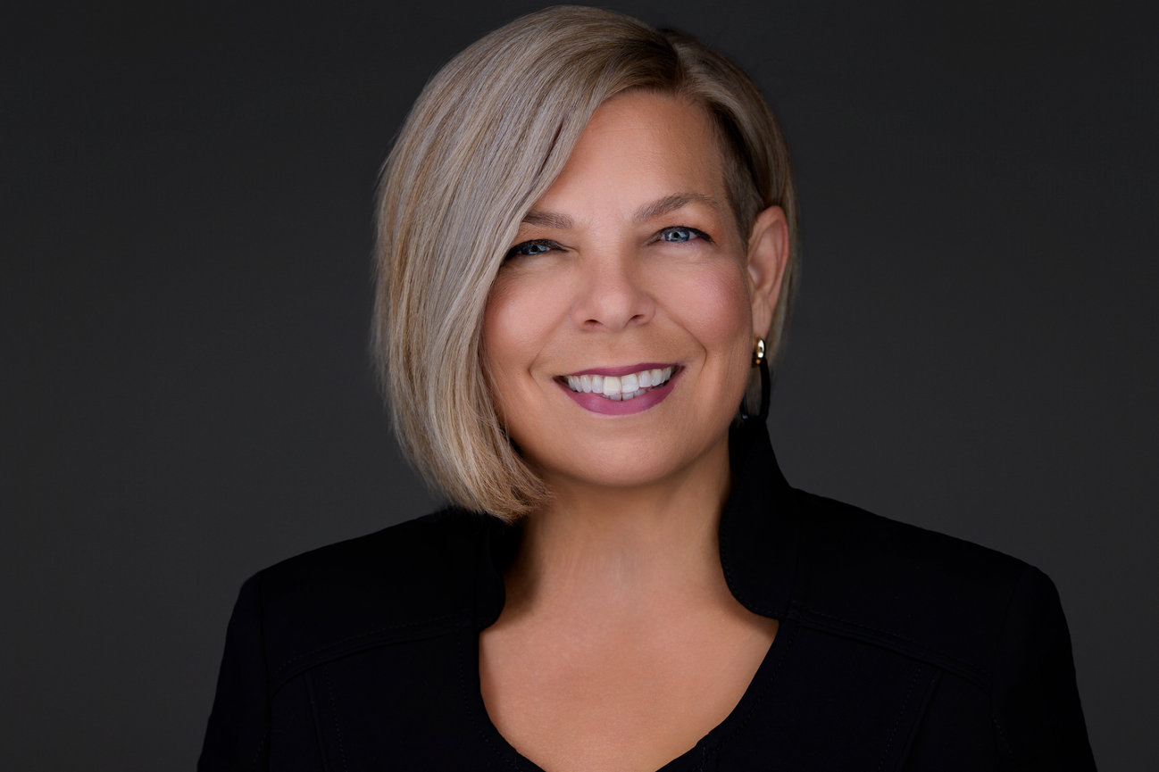 Smiling woman in black blazer with short blonde hair, executive studio headshot by professional DFW headshot photographer