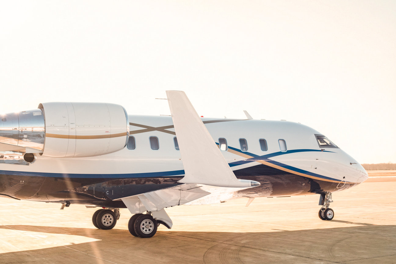 Private jet on a sunlit tarmac, featuring sleek design and blue accents.