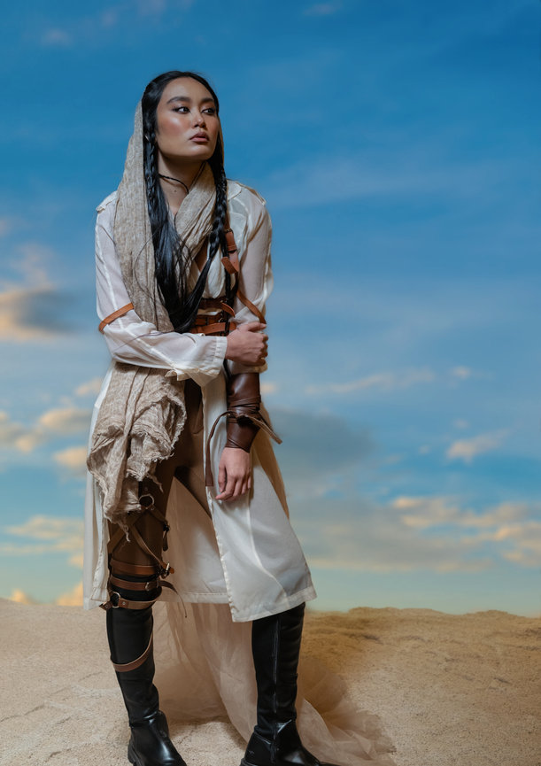 Model in desert-inspired fashion posing on sandy terrain with blue sky