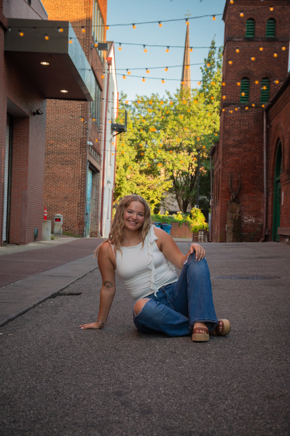 Woman sitting in an alleyway with lights overhead