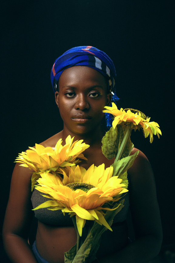 Woman holding sunflowers against dark background
