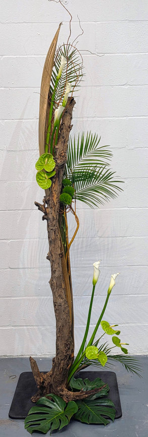Tall floral arrangement with leaves and branches