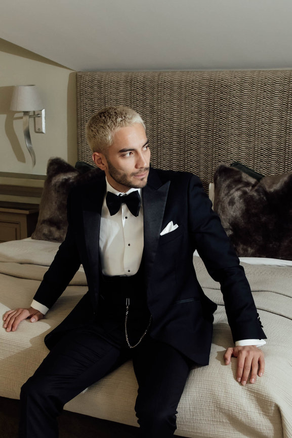 Editorial groom portrait at Fernside House & Barn: a groom in a classic tuxedo posing in a refined bedroom setting.
