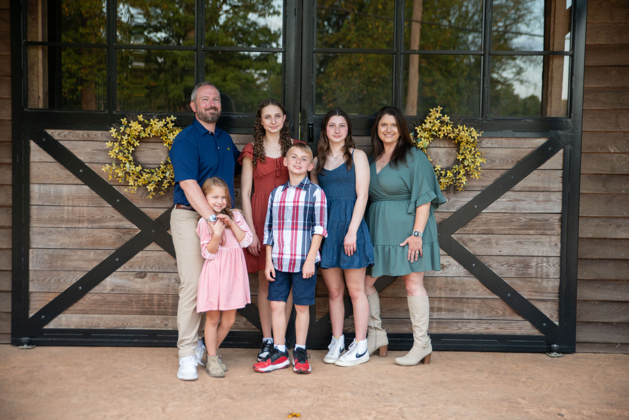 Family standing together in front of a large wooden gate.
