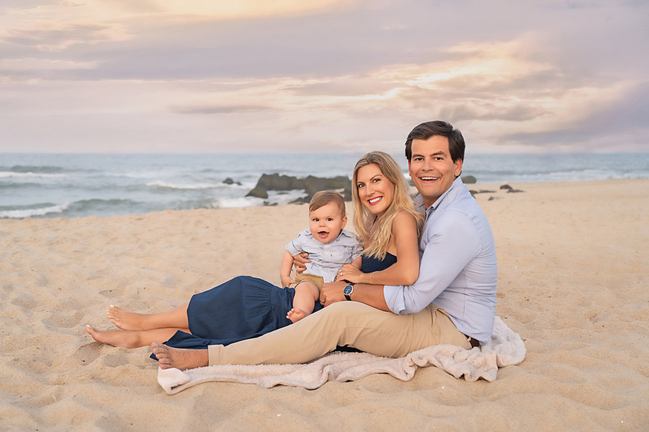 Family seated on beach blanket, relaxed and smiling