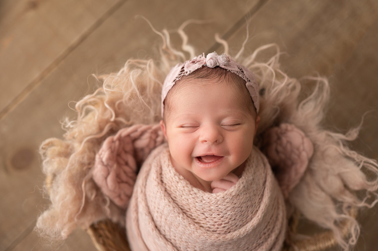 Newborn baby swaddled in textured knit wrap, sleeping peacefully in basket during studio session in Manasquan, NJ