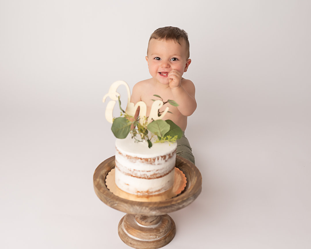 Minimalist cake smash setup in Shrewsbury, NJ with white cake and greenery accents