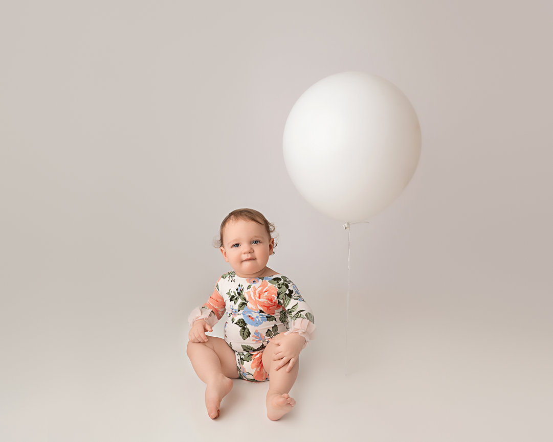 Joyful toddler holding large balloon in clean, modern Millstone, NJ studio