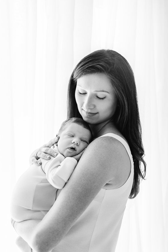 Mother holding baby close by sunlit window in Kristin Baker’s Princeton photography studio