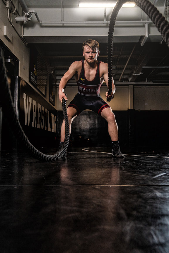 Athlete in a wrestling gym working out with battle ropes.