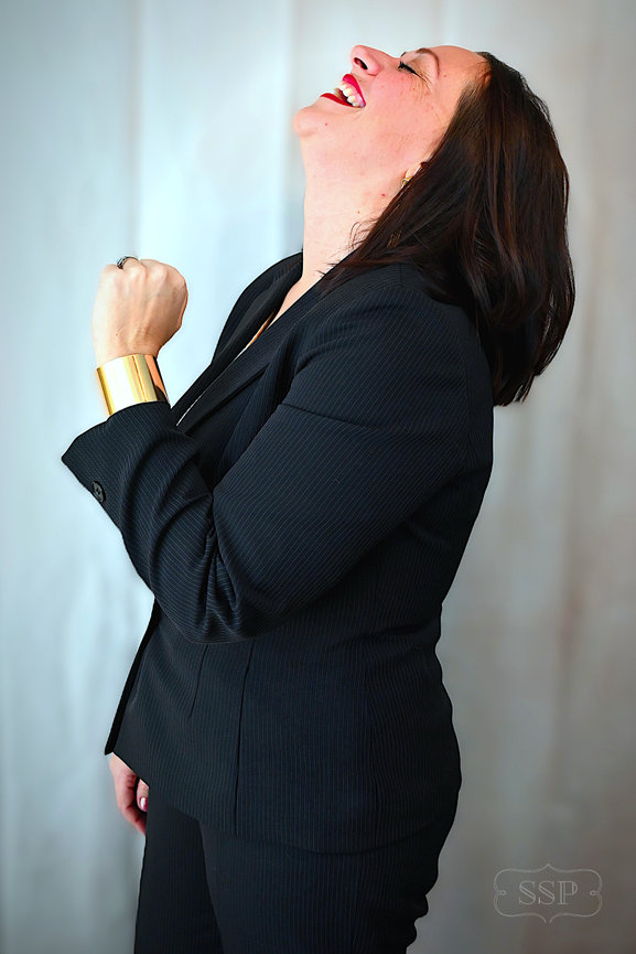 Portrait of a woman laughing with her head tilted back against a light background