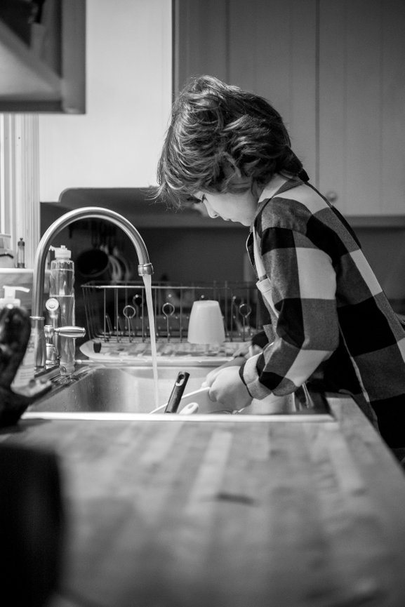 Young white boy, black and white storytelling, young boy washing dishes, Photography by Heather Raub of FrontRoom Images