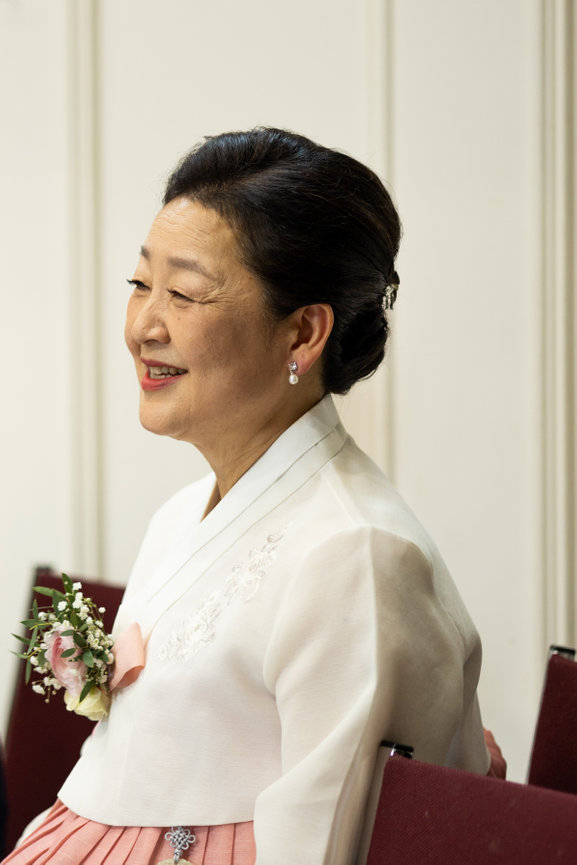 Group of four people posing together indoors, one holding a bouquet, wedding photography