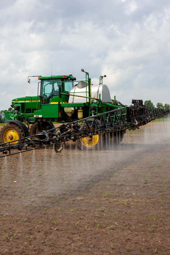 A farmer spraying a field crop during the growing season.