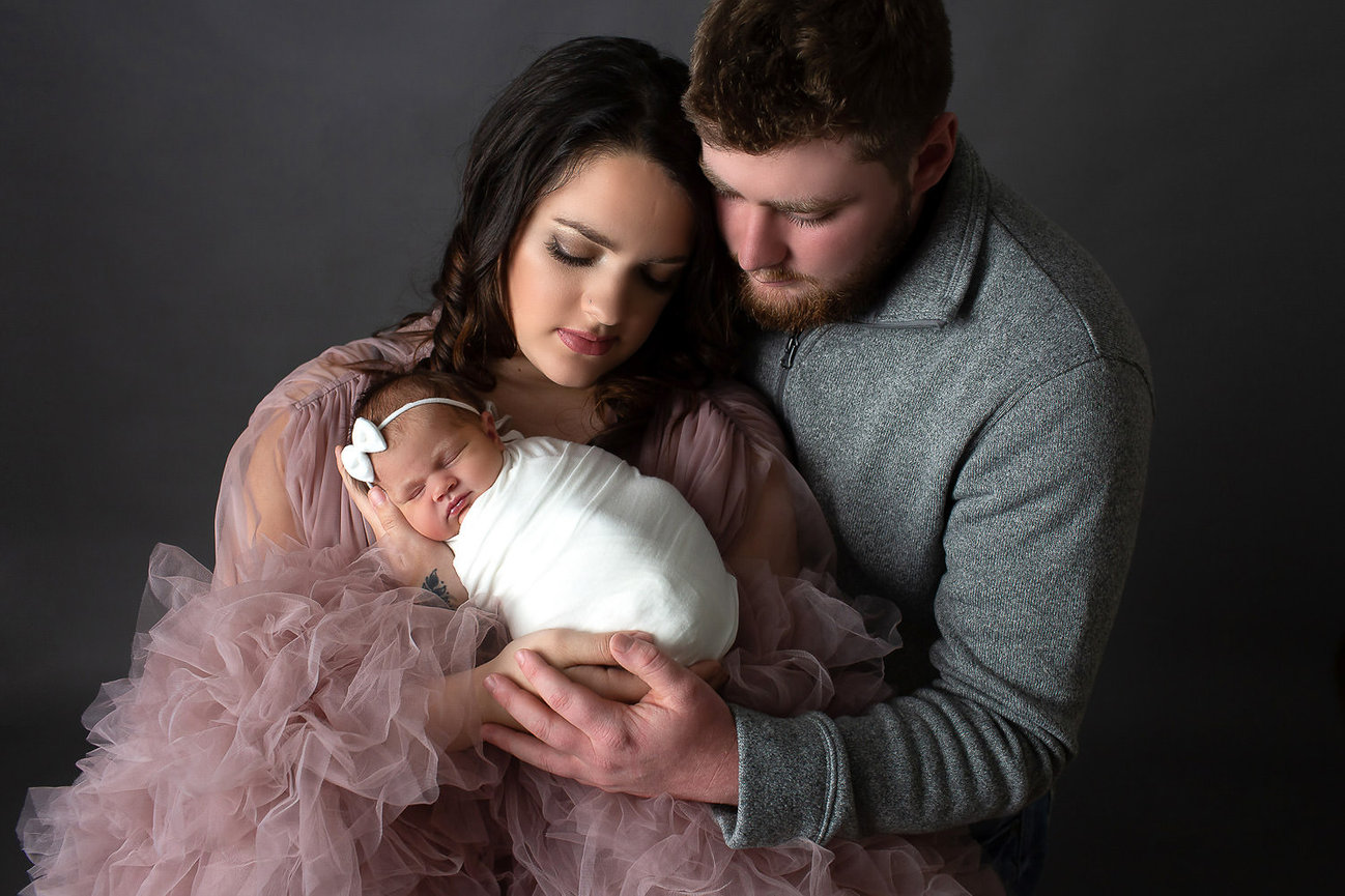 Mom and dad snuggling newborn baby during newborn photo session with newborn photography Dreamworks Photography in Kansas City Kansas