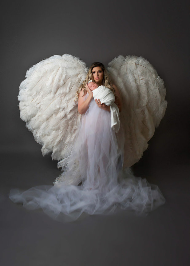 Mother wear white angel wings holding her newborn baby girl during newborn photography session with kansas city newborn photographer Dreamworks Photography