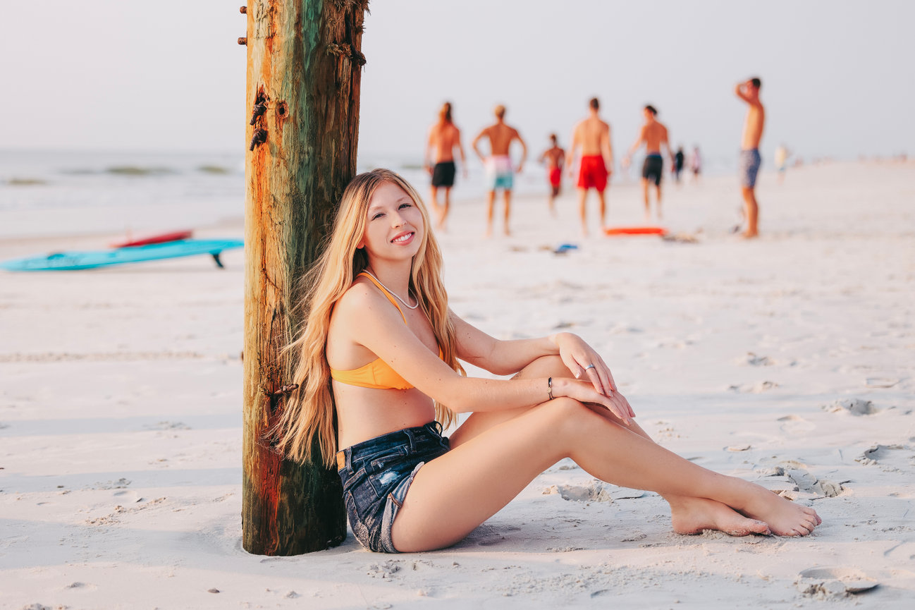 A young woman with strawberry blonde hair posing confidently in downtown Jacksonville, Florida for her high school senior photoshoot downtown Jacksonville, Fl in front of a colorful mural with butterfly wings, exuding a sense of style.