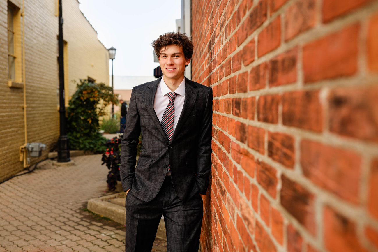 High school senior boy posing by brick wall