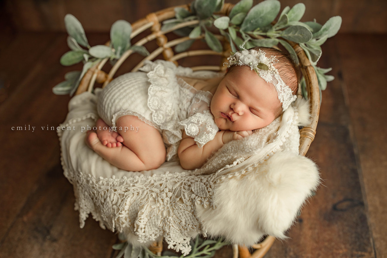Newborn baby in all white laying against cozy white blankets