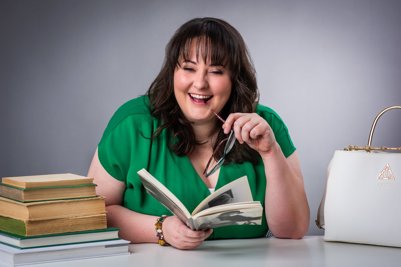 Woman sitting at a desk in a photo studio laughing while looking at books posing for a branding photo shoot in Salt Lake.