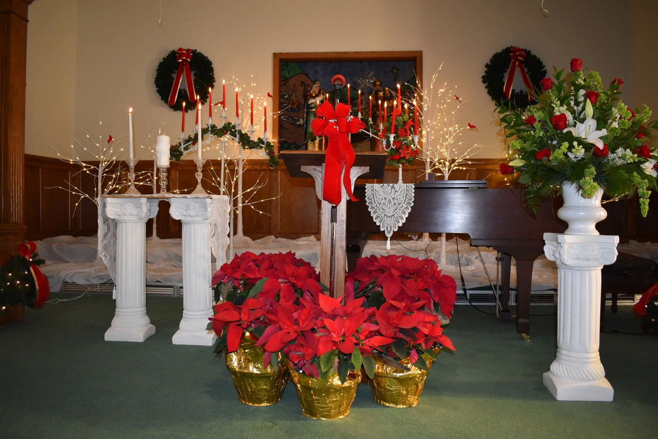 Candlelit church altar with flowers and white pedestals
