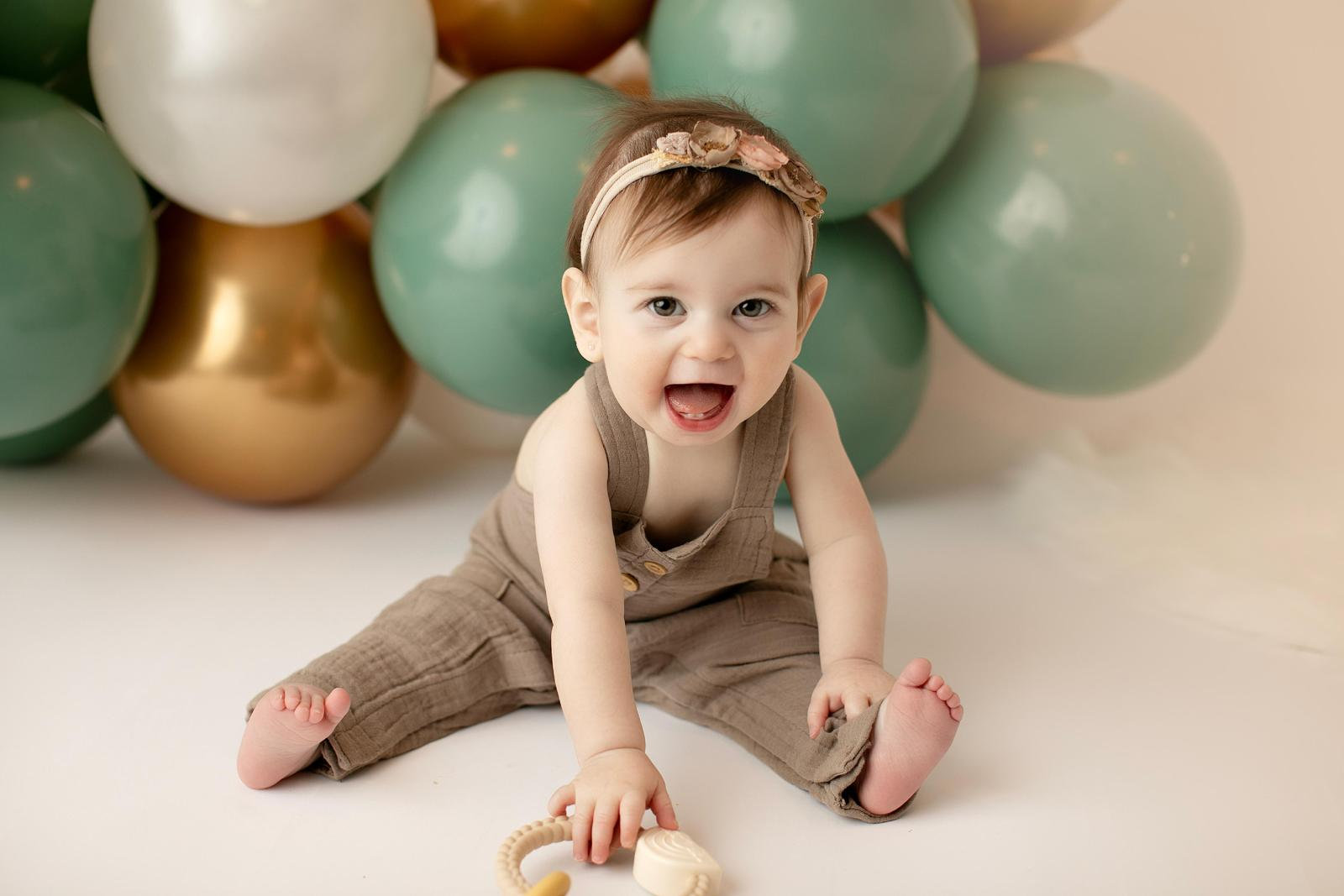 Baby laughing beside a sage balloon arrangement