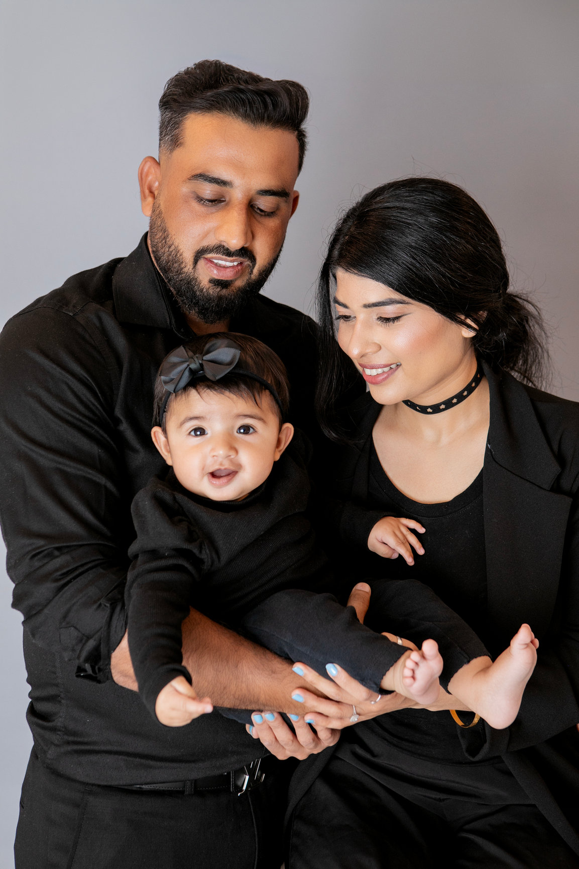Parents holding their baby close against a grey studio backdrop