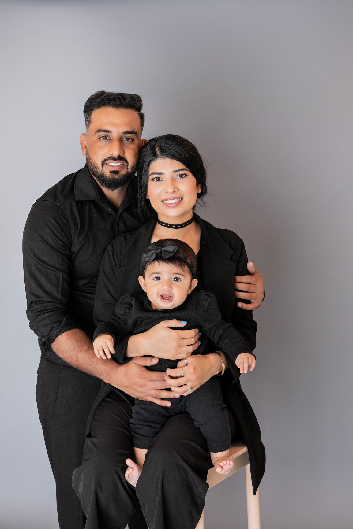 Family in coordinated black outfits posing together in the studio