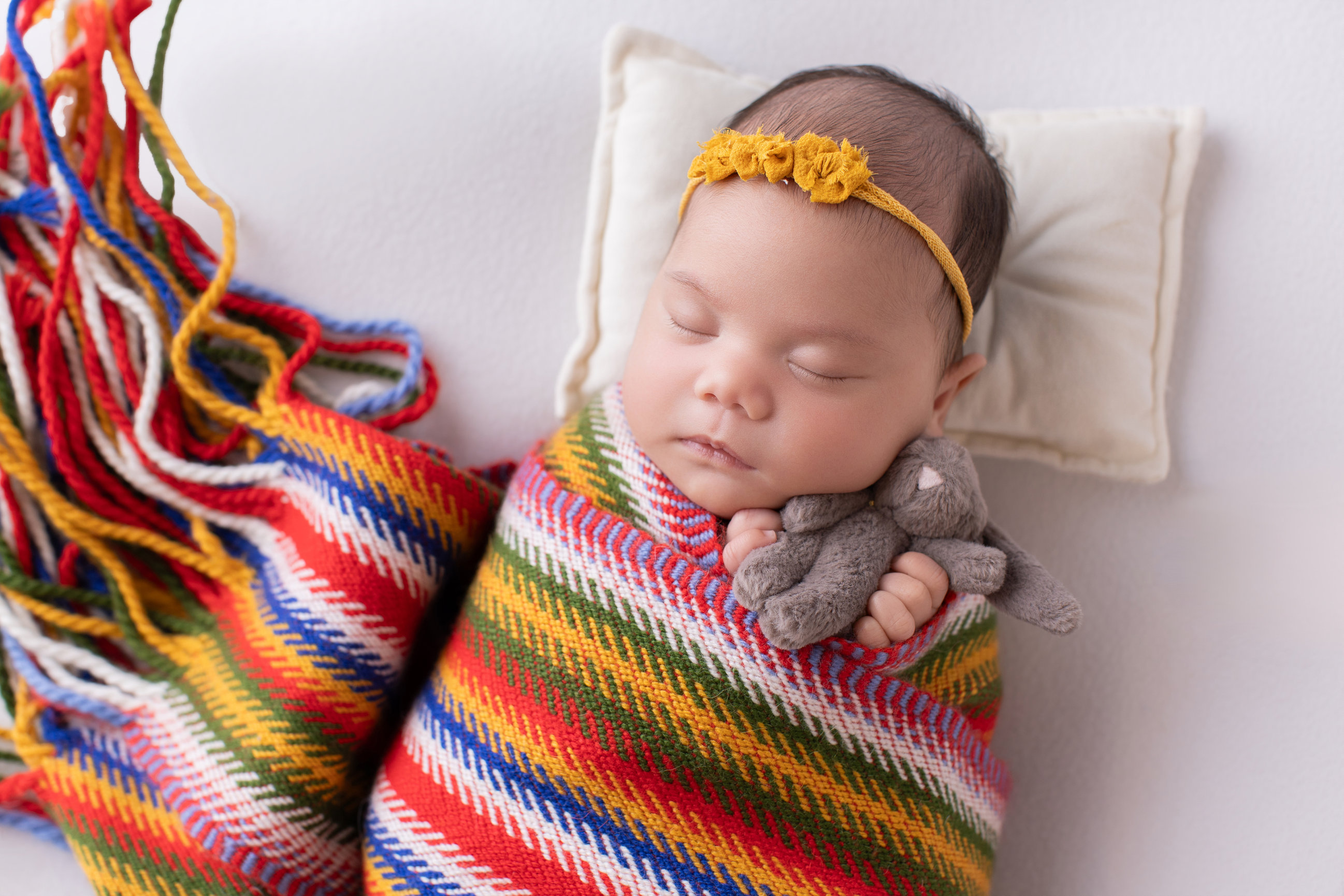 Newborn girl asleep wrapped in a Métis sash with its fringed ends laid out beside her