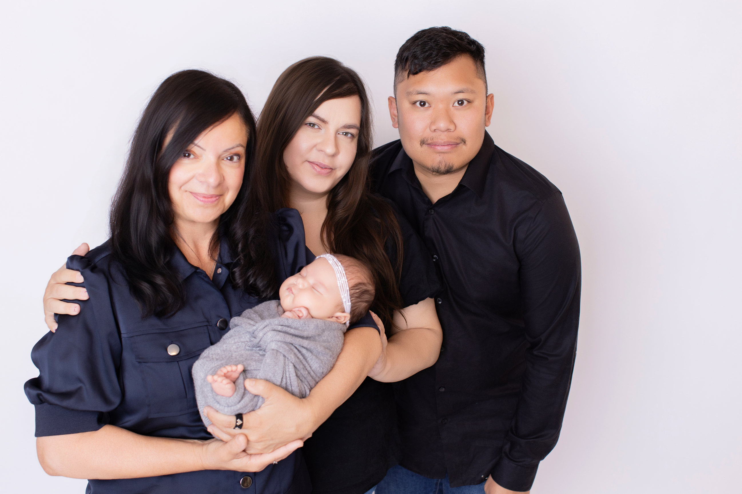 Mother, father and grandmother together with the newborn baby girl in a Calgary studio