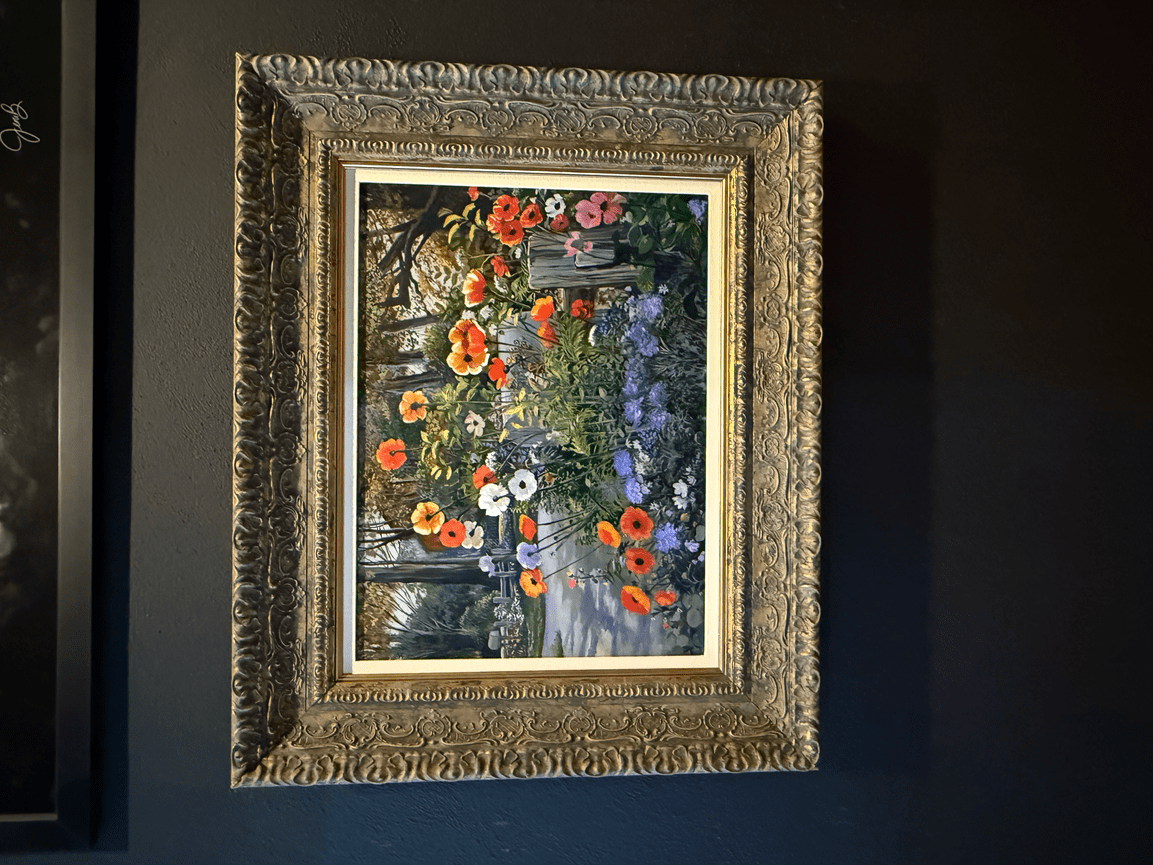 Framed floral artwork with colorful flowers displayed on a dark wall