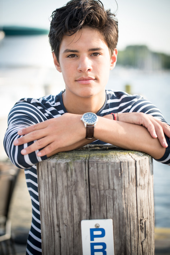 teenage boy in a navy and white shirt leaning against a wooden pier in Dublin OH.