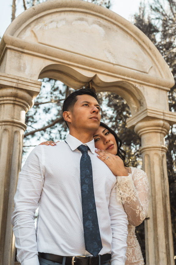Couple embracing under a stone arch outdoors