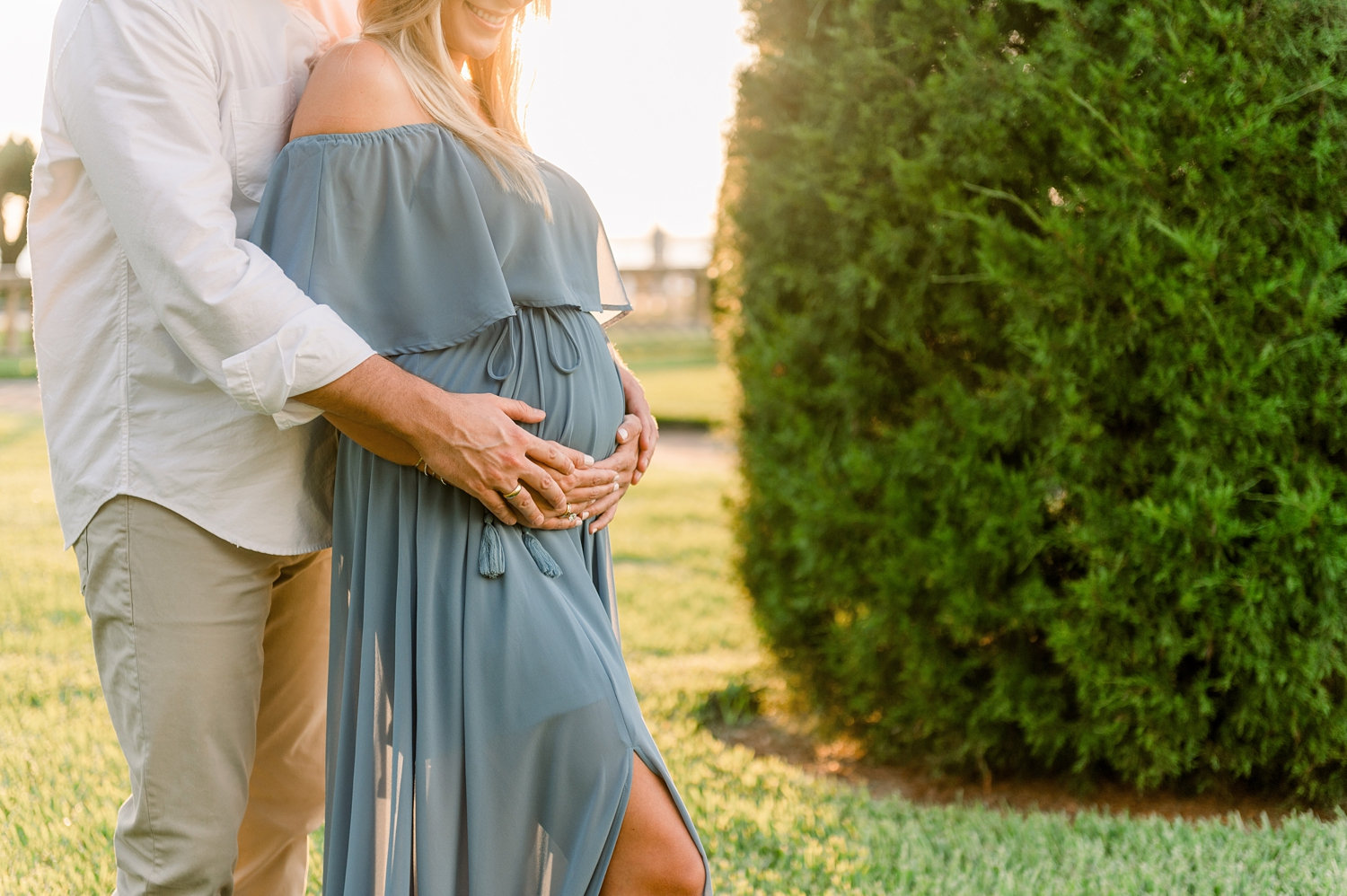 couple standing together, holding her pregnant baby bump, beautiful garden in Jacksonville, Florida