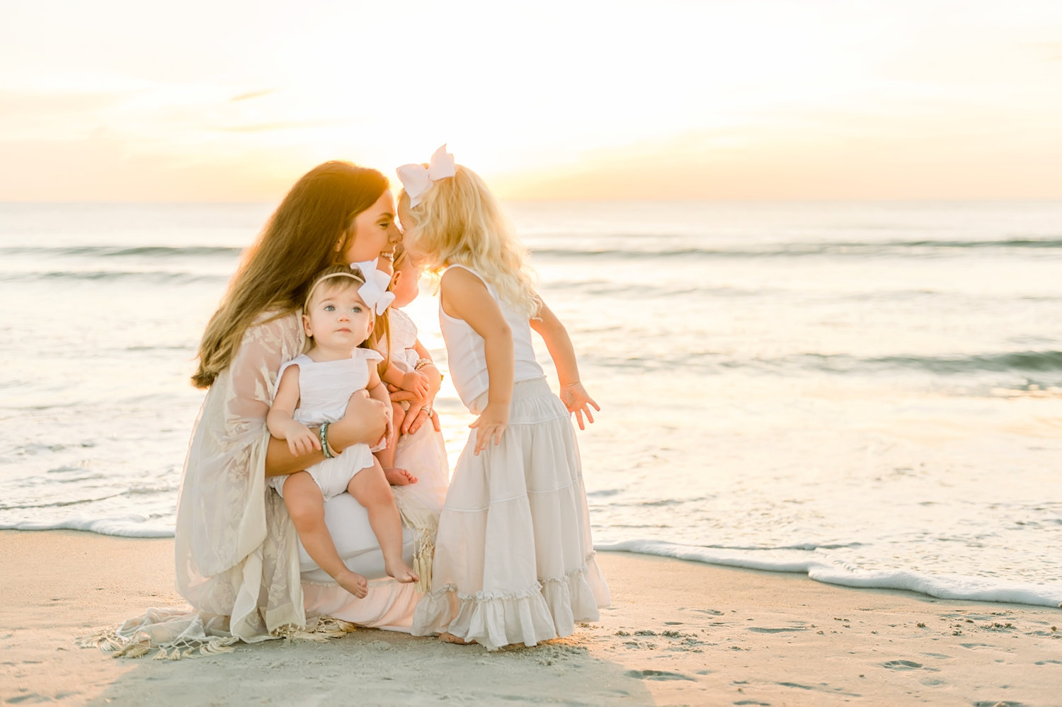 mom kneeling and holding twin baby girls, mom touching noses with her little girl