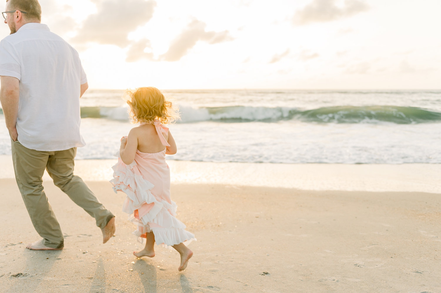 dad and his little girl running along St. Augustine Beach at sunrise