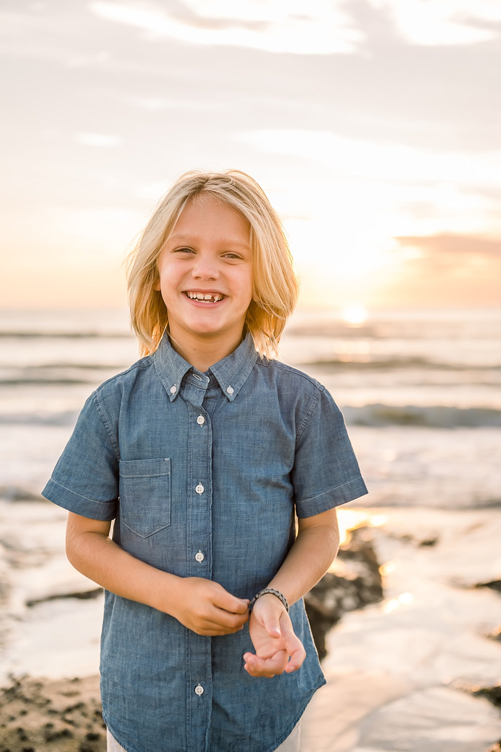 portrait of a little boy on Saint Augustine Beach, he is wearing a short sleeved denim shirt